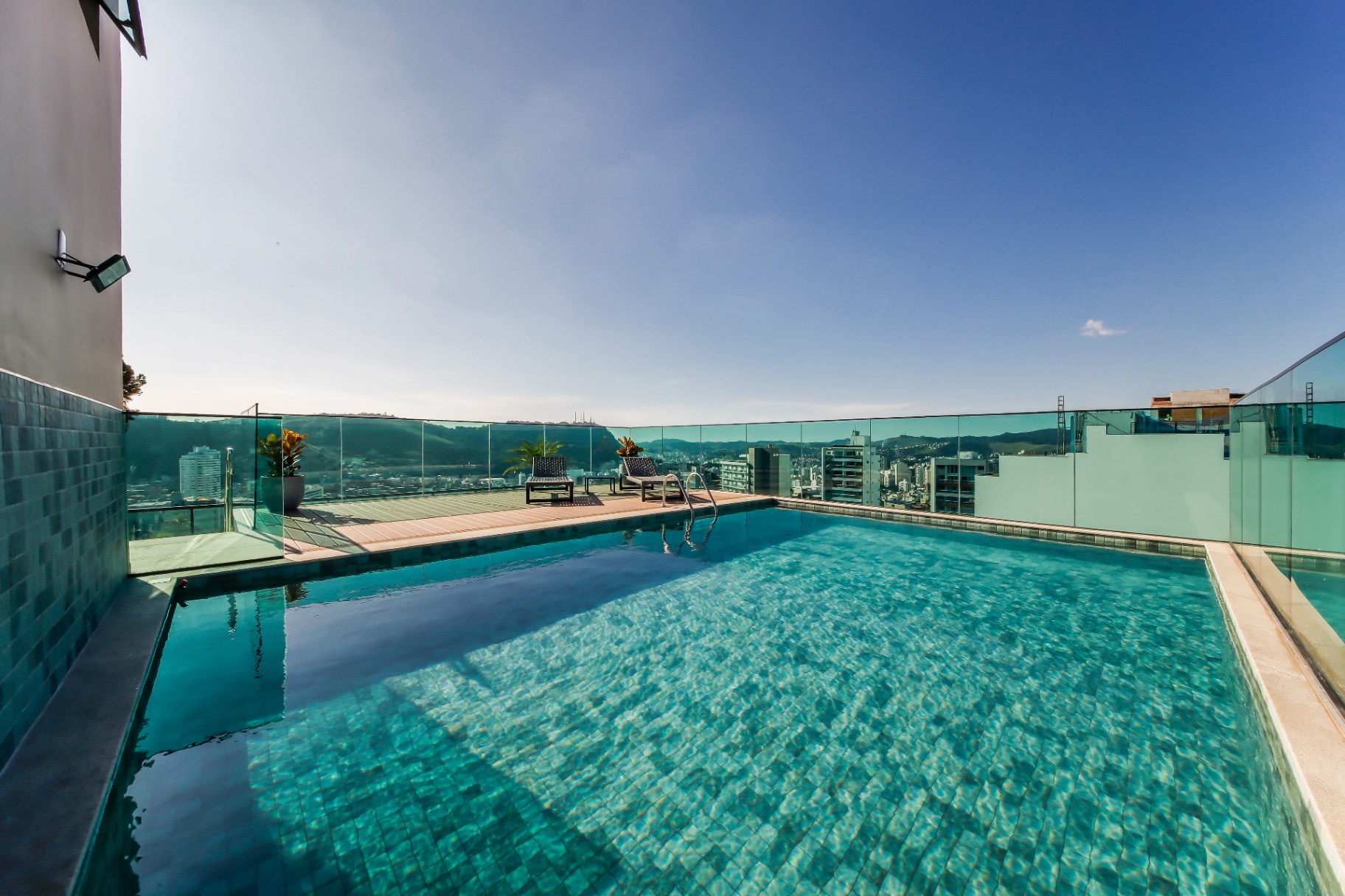 Piscina do rooftop em deck de madeira com guarda-corpo em vidro